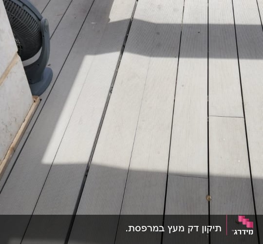 אדם מחזיק נדנדה אדומה על רצפת עץ בגינה